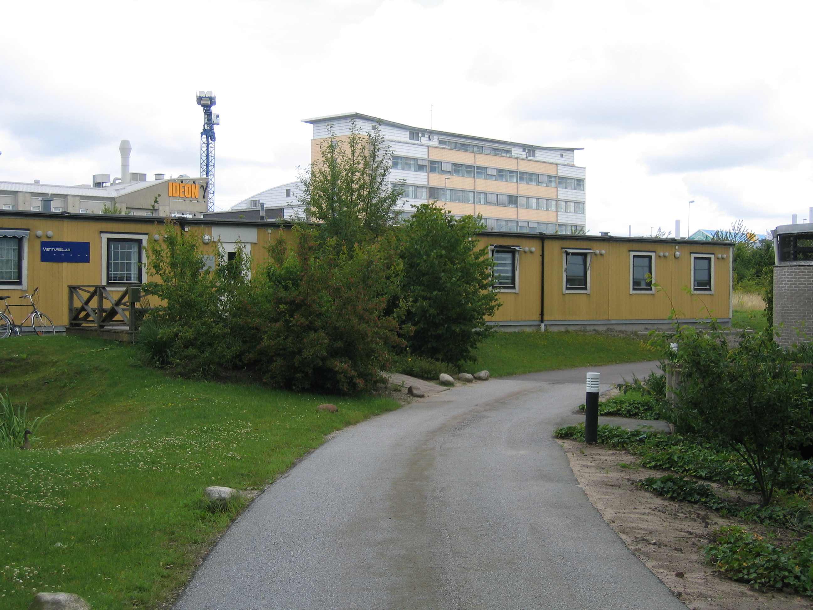 A picture of the VentureLab offices as seen from the outside, showing a one-story yellow building with a taller building in the background.